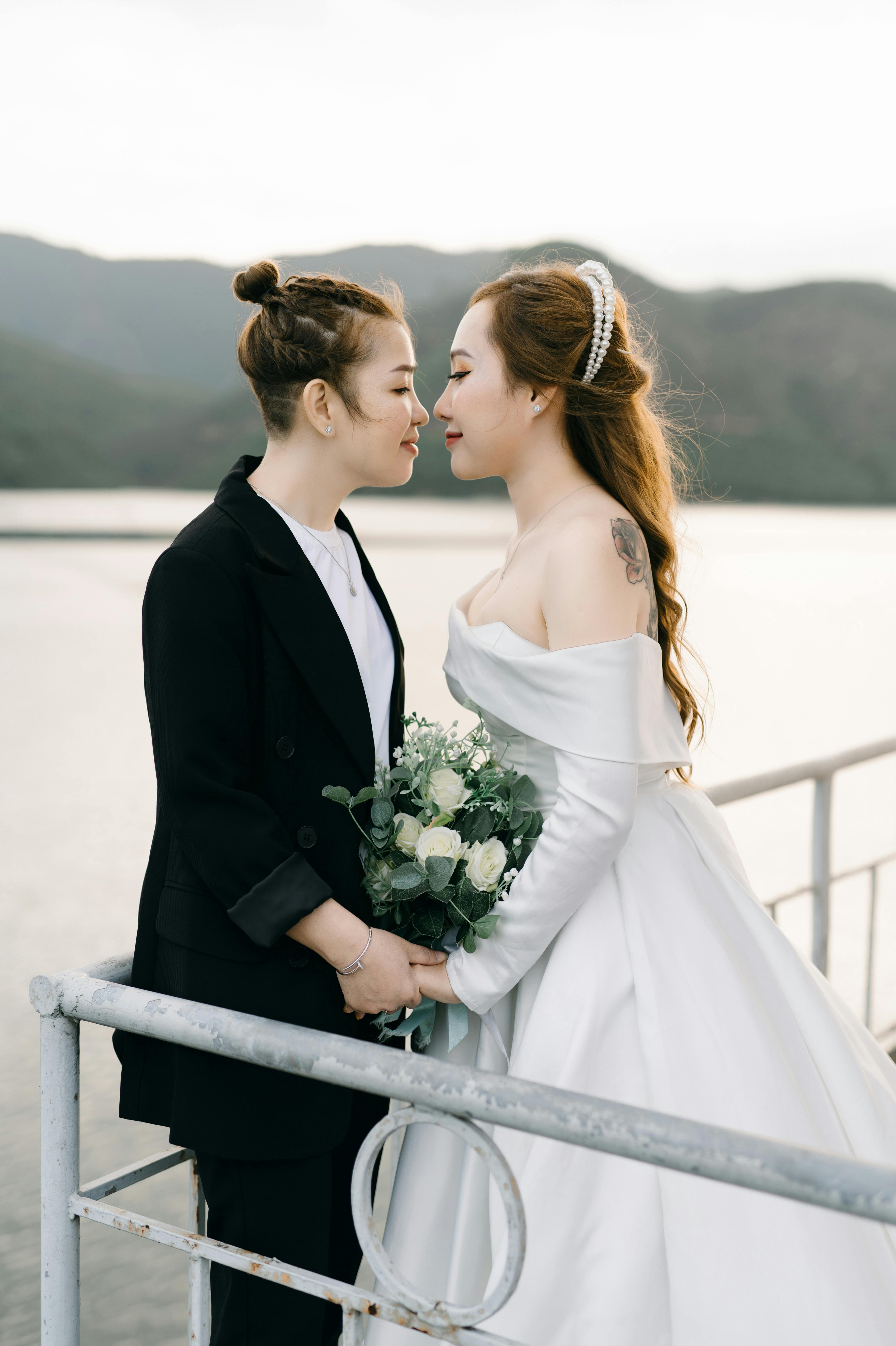 newlywed women standing on jetty holding hands