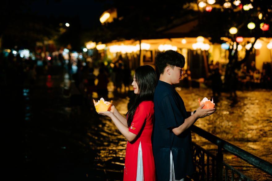 Two people releasing paper lanterns by the river at night — Trần Long on Pexels