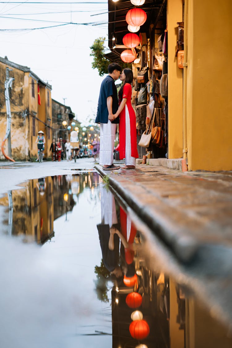 Couple Kissing On Street Reflecting In Puddle