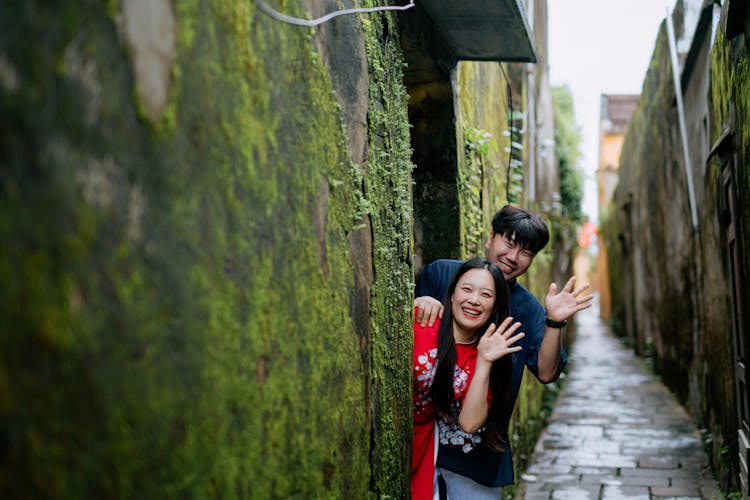 Photo Of A Couple Smiling While Waving Their Hands