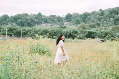 Woman in White Dress Walking on a Green Grass Field