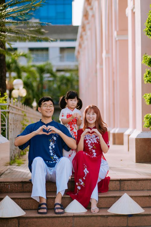 Free Family with child in traditional attire showing love gestures outdoors. Stock Photo