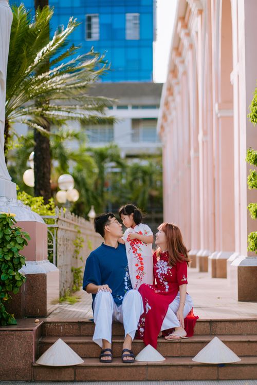 Free Happy family sitting on city stairs surrounded by lush greenery and architecture. Stock Photo