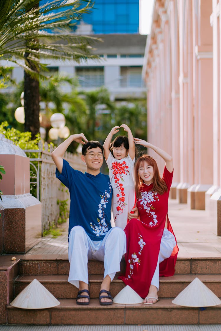 Family Sitting On Stairs Doing Love Hand Sign