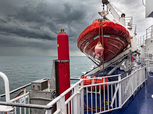 Red Lifeboat Aboard a White Ship on Sea