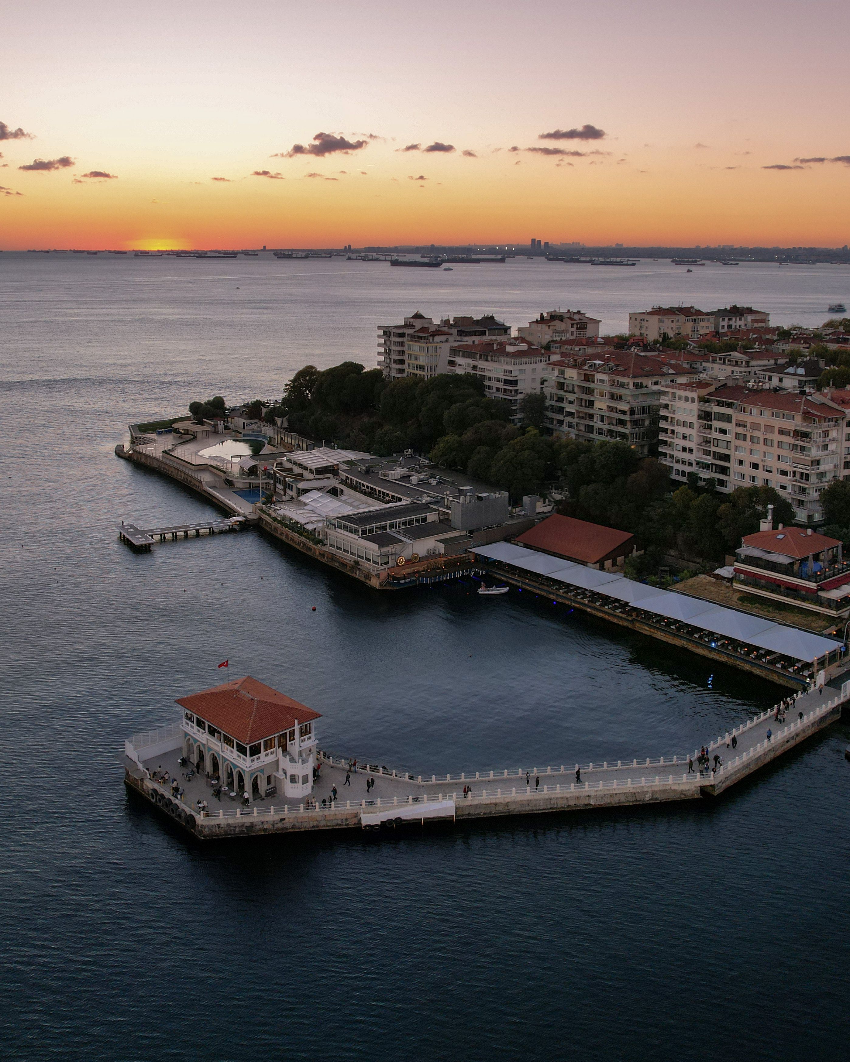 Aerial view of the Kadıköy Pier at sunset in İstanbul, Türkiye, showcasing the vibrant cityscape and calm sea.