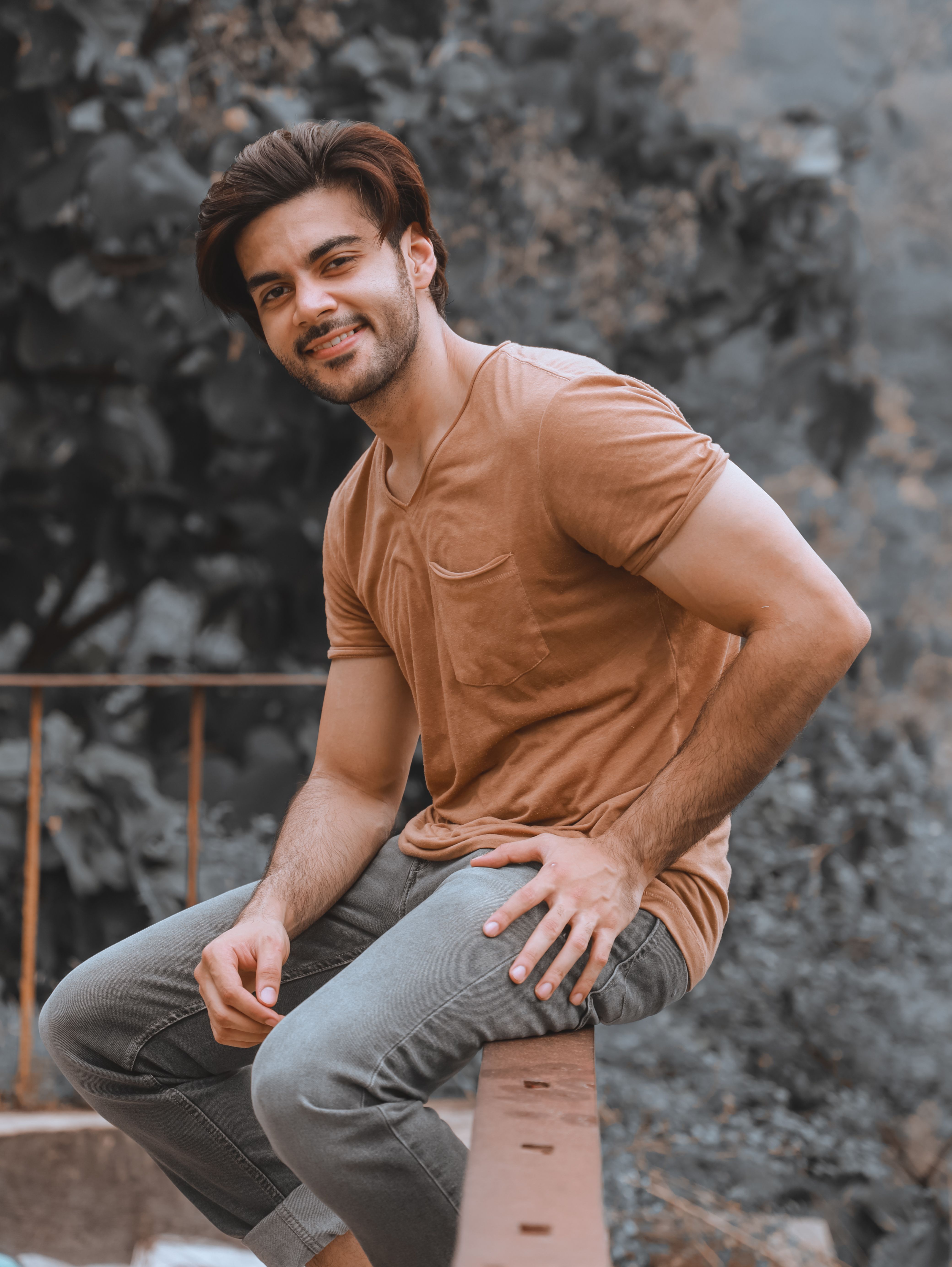 A smiling man with facial hair sitting outdoors in a casual pose.