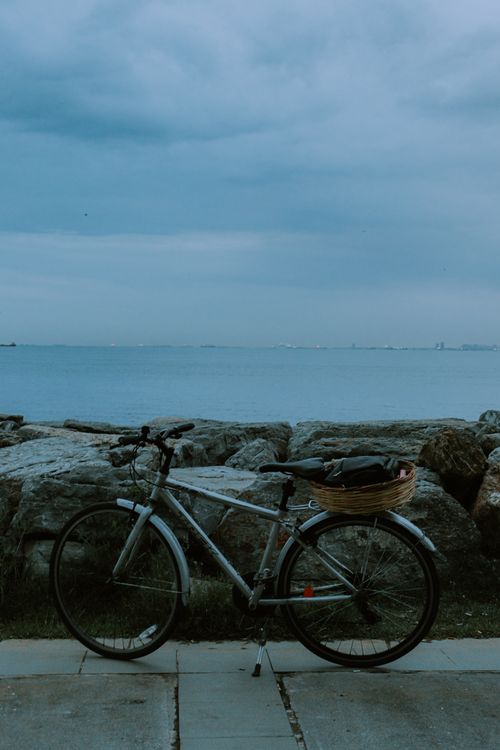 Free Bicycle parked by rocks with a tranquil ocean backdrop at twilight. Stock Photo