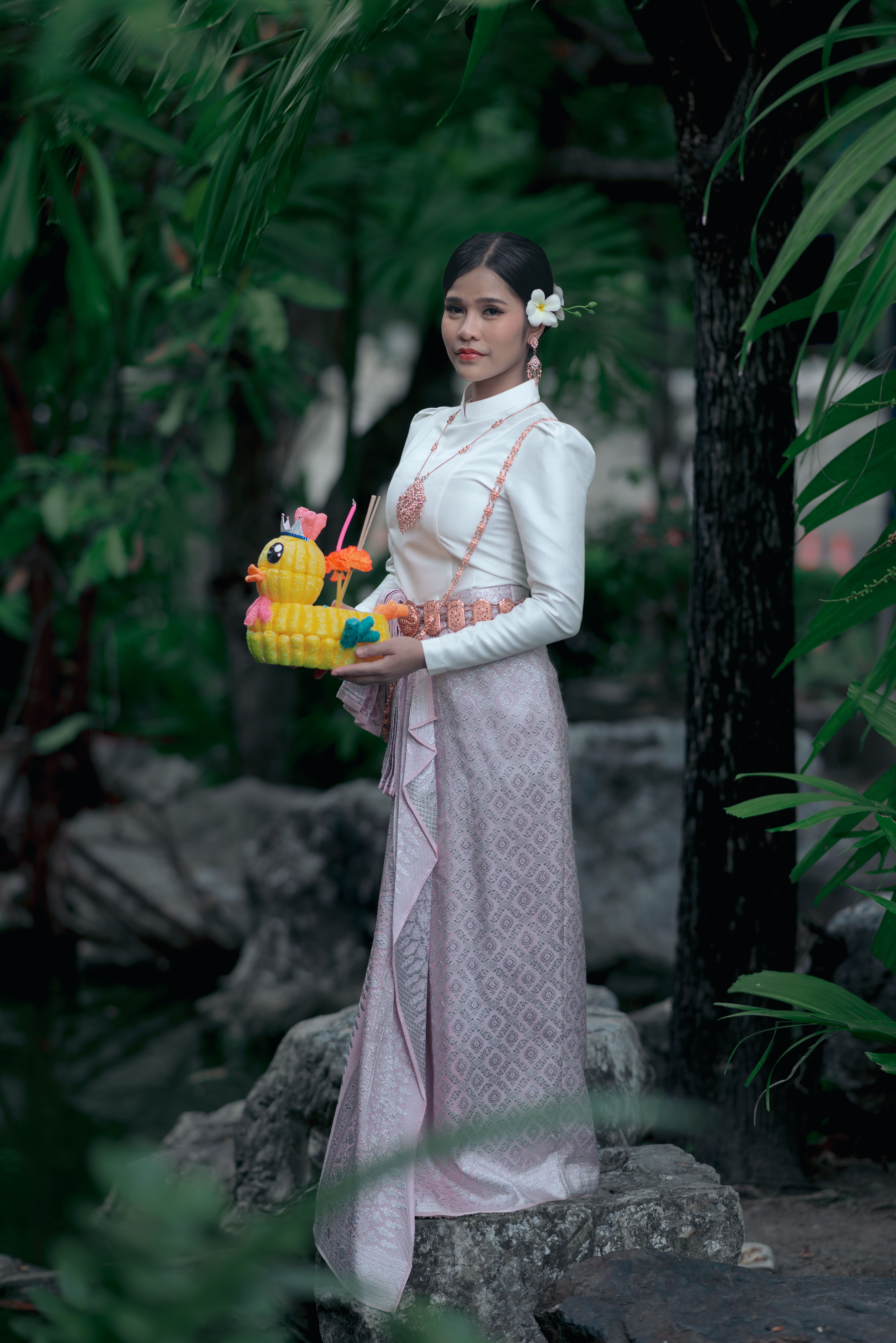 Young Asian woman in traditional dress holding a colorful float outdoors.