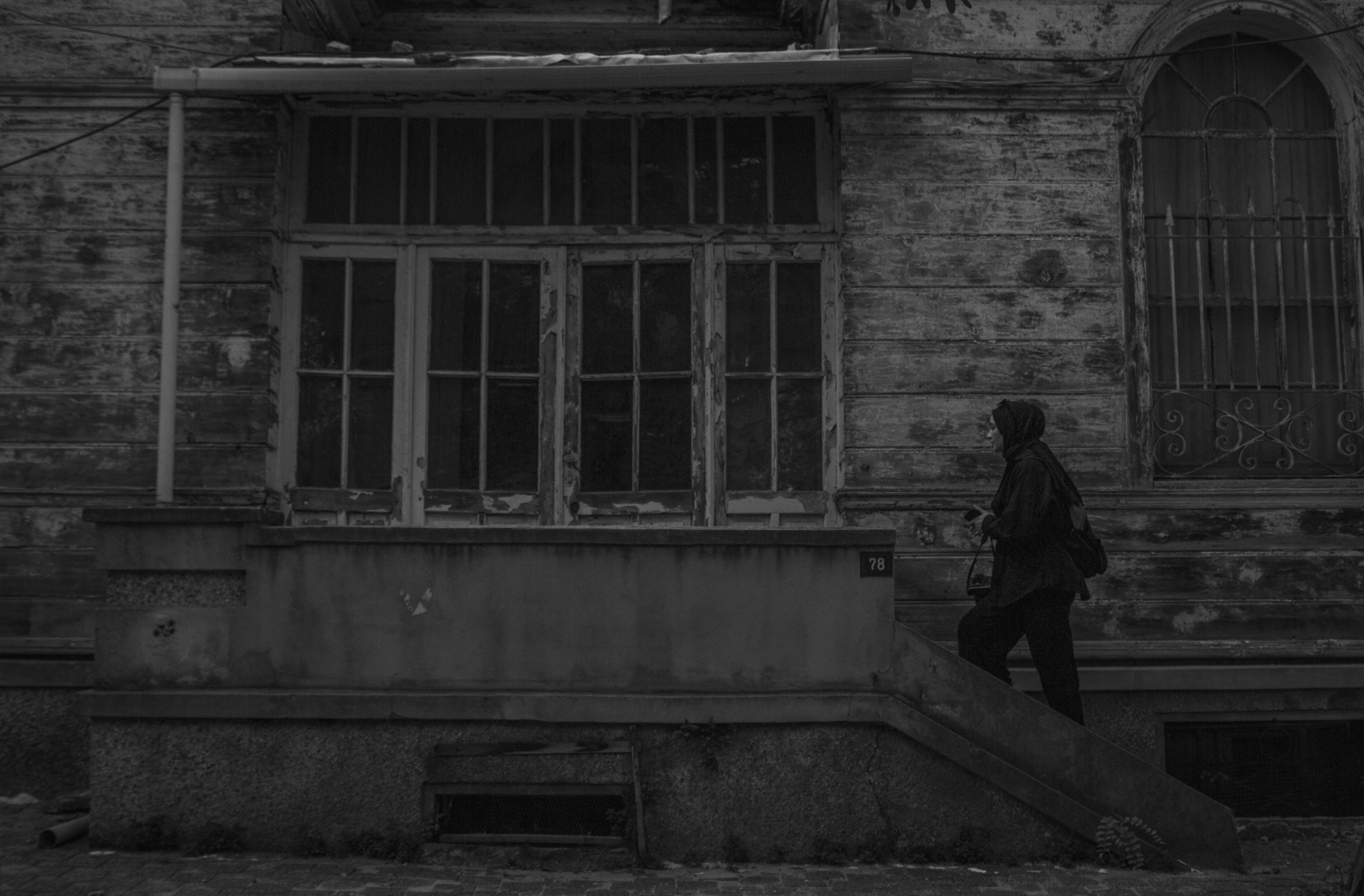 Woman in Headscarf Walking up the Steps of an Abandoned House Porch ...
