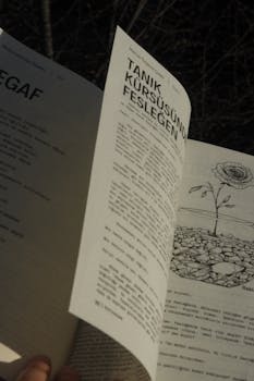 Close-up of an open book with detailed illustration of a plant, featuring text in another language.