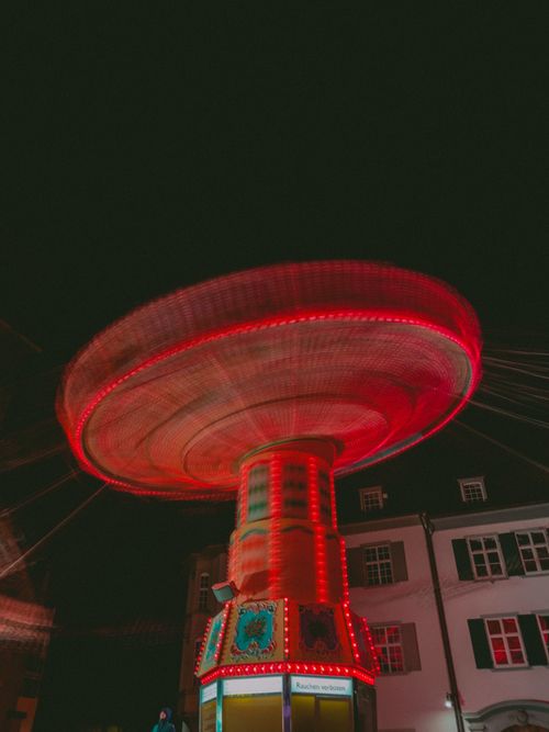 Free Blurred motion of a colorful carnival swing ride at night with urban backdrop. Stock Photo