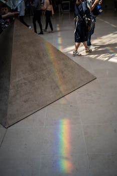 博物馆地板上的金字塔结构附近，色彩缤纷的光线反射出彩虹图案