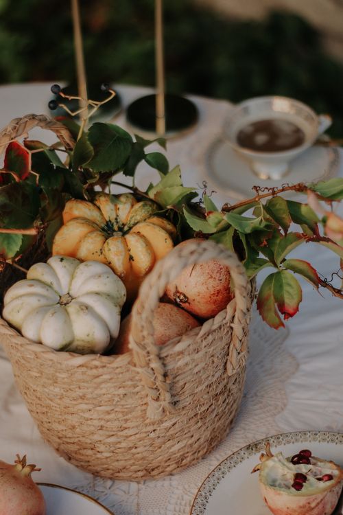 Free A woven basket filled with pumpkins and fruits, set on a table with elegant tableware. Stock Photo