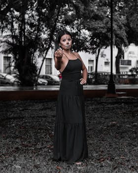 A woman in a black dress with Day of the Dead makeup posing outdoors, reflecting cultural celebration.