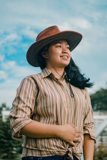 A cheerful woman wearing a cowboy hat enjoys the sunny outdoors, capturing a carefree summer vibe.