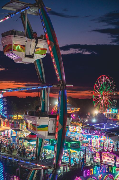 Free Colorful amusement park with illuminated rides at sunset, showcasing a lively atmosphere. Stock Photo