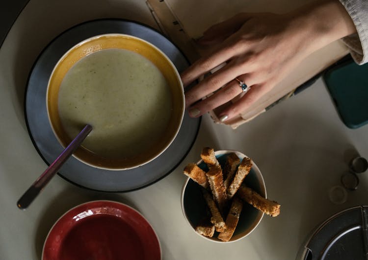 Overhead Shot Of A Person's Hand Near A Bowl Of Soup