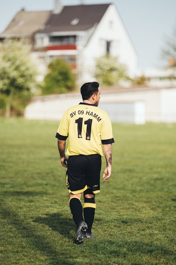 Man In Yellow Jersey Walking On Grass