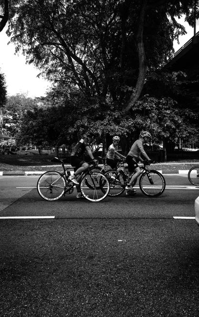 A group of cyclists riding together on a city street, captured in black and white.