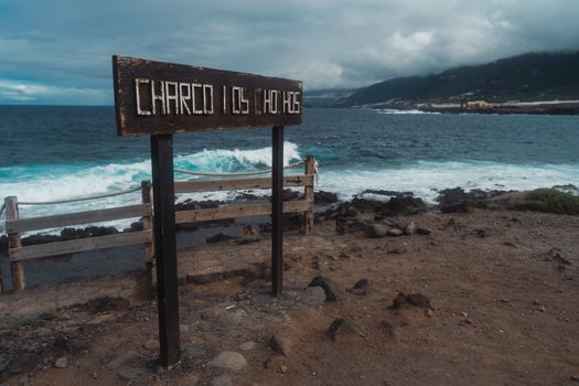 Rustic wooden sign by the ocean at a rocky shore. Perfect for travel themes.