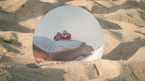 Baby Shoes on Belly of Pregnant Woman Reflecting on Round Mirror