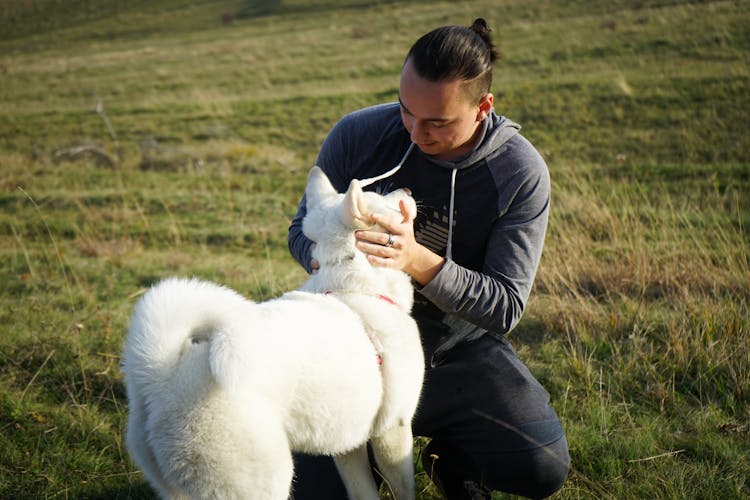 A Man Petting A White Dog