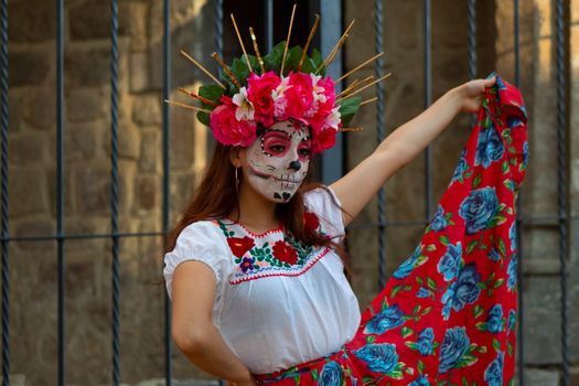 Vibrant portrait of a woman in traditional Day of the Dead makeup and attire with a floral headdress.