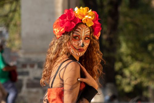 Free Vibrant Dia de los Muertos makeup with floral headdress in outdoor festival setting. Stock Photo