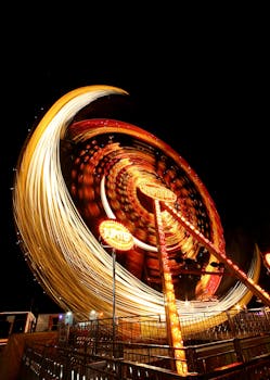 这张长曝光照片充满活力，捕捉了夜间摩天轮的运动与灯光