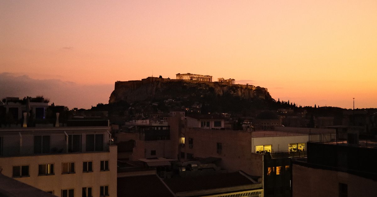 A stunning view of Athens featuring the Acropolis against a vibrant sunset sky.