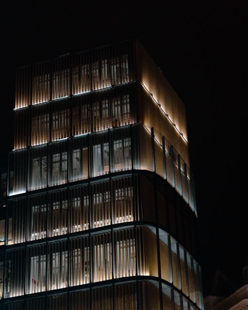 Free A night view of a modern illuminated office building, showcasing urban architecture. Stock Photo