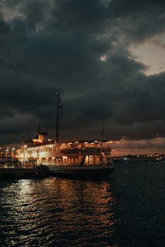 A ferry illuminated at night in a stormy ocean setting, creating a dramatic scene.