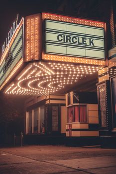 Vintage theater entrance illuminated by marquee lights with 'Circle K' sign at night.
