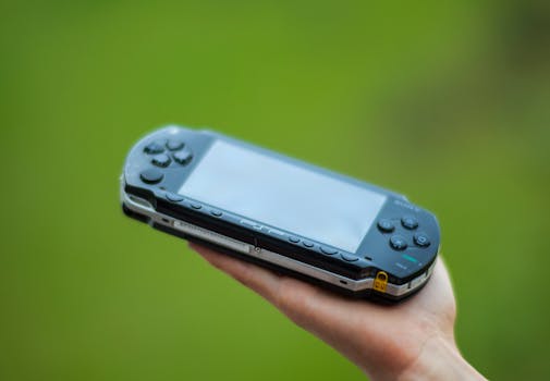 A hand holding a portable gaming console against a vibrant green background, showcasing modern technology.
