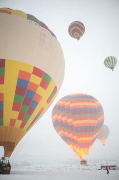 Vibrant hot air balloons ascending on a bright snowy day.