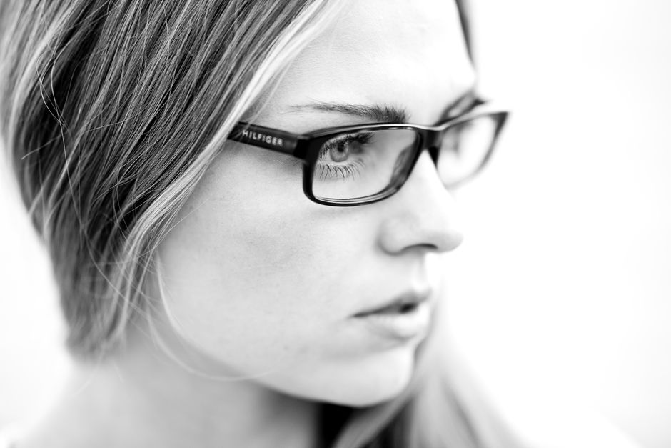 Artistic black and white portrait of a woman wearing glasses, emphasizing style.