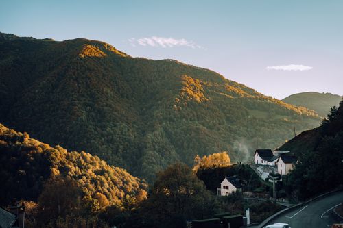Free A picturesque village nestled in mountainous terrain under a clear blue sky during golden hour. Stock Photo