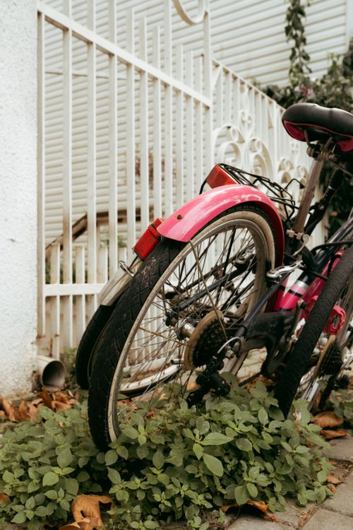 Free A parked bicycle next to a white fence with greenery below, conveying urban calm. Stock Photo