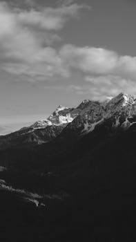 Breathtaking black and white view of snow-covered mountains under cloudy skies.