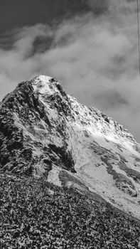 Gorgeous black and white capture of a snow-covered mountain peak in a dramatic landscape.