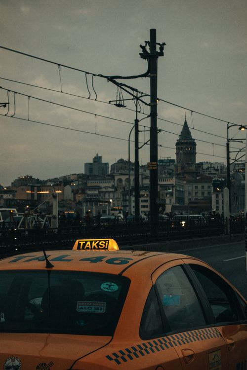 Free Orange taxi in the foreground with Galata Tower in the background during sunset in Istanbul. Stock Photo