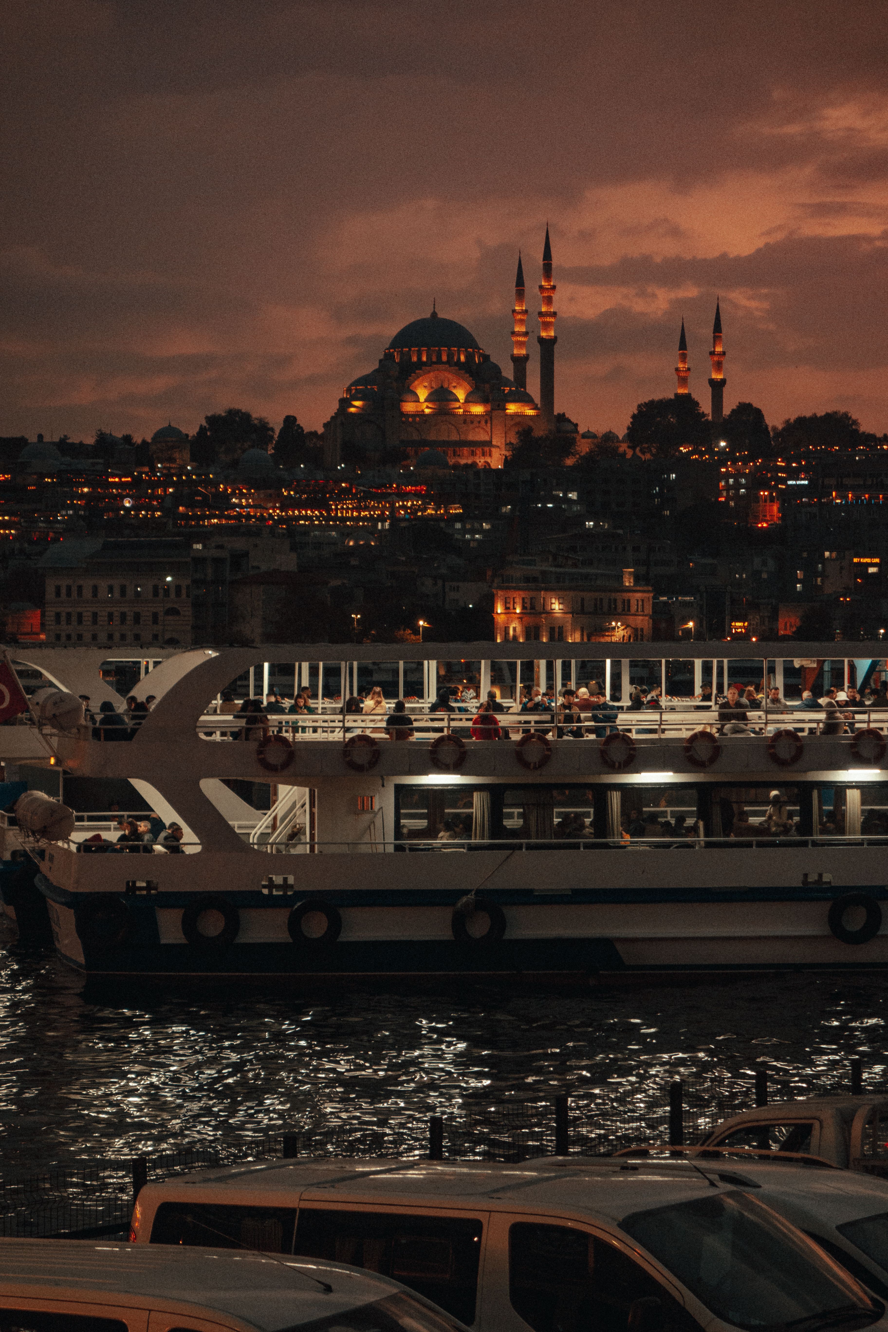 A cruise ship sails past Istanbul's iconic skyline at dusk, highlighting the illuminated cityscape and Bosphorus waters.