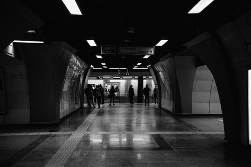Free Moody black and white view of a subway station corridor with people waiting. Stock Photo