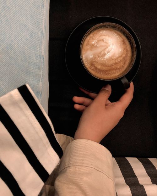 Free Hand holds a coffee cup, exuding warmth and relaxation indoors. Stock Photo