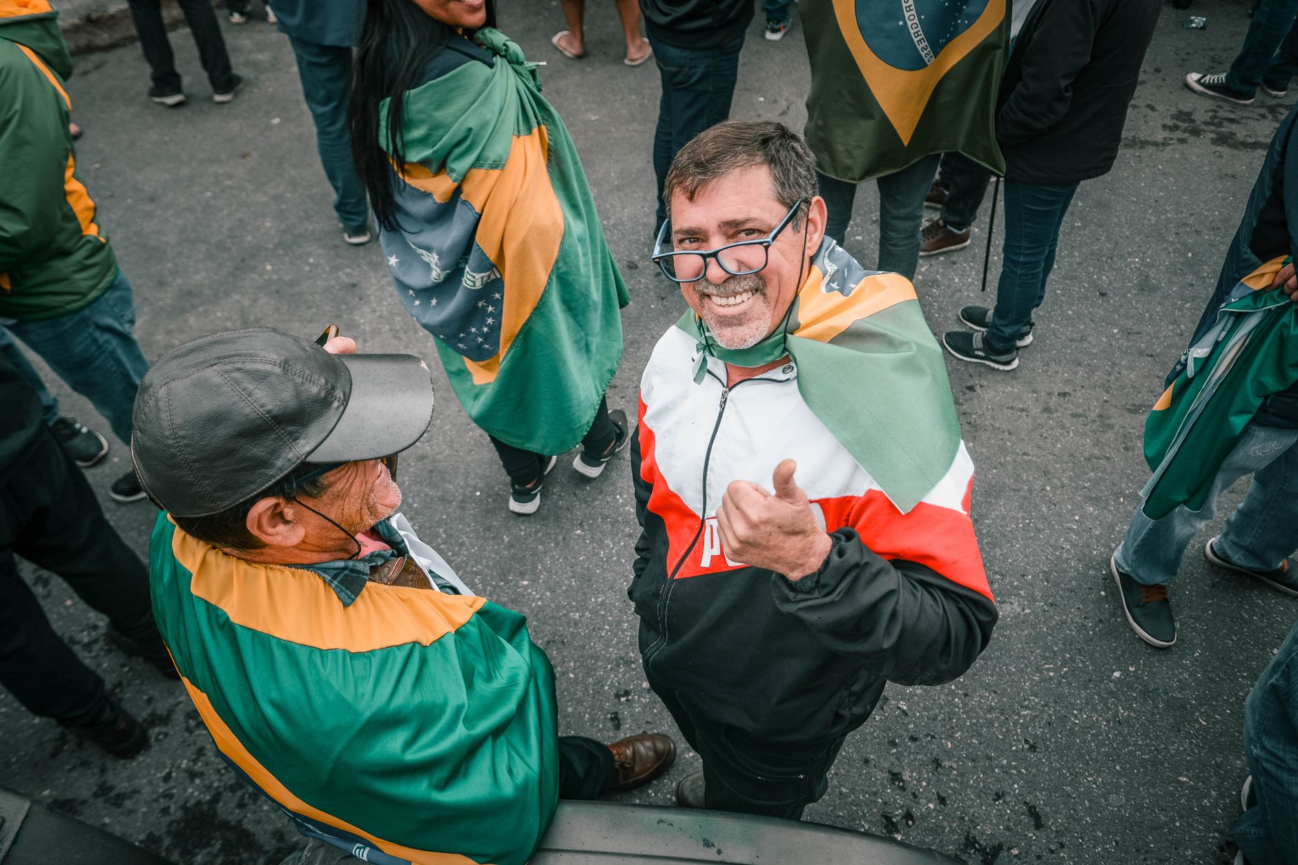 Cheerful crowd displaying Brazilian pride with flags on a city street.