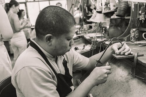 Monochrome Photo of a Factory Worker Using a Coping Saw