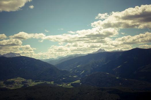 Breathtaking view of mountainous landscape with clouds, valleys, and lush greenery on a summer day.