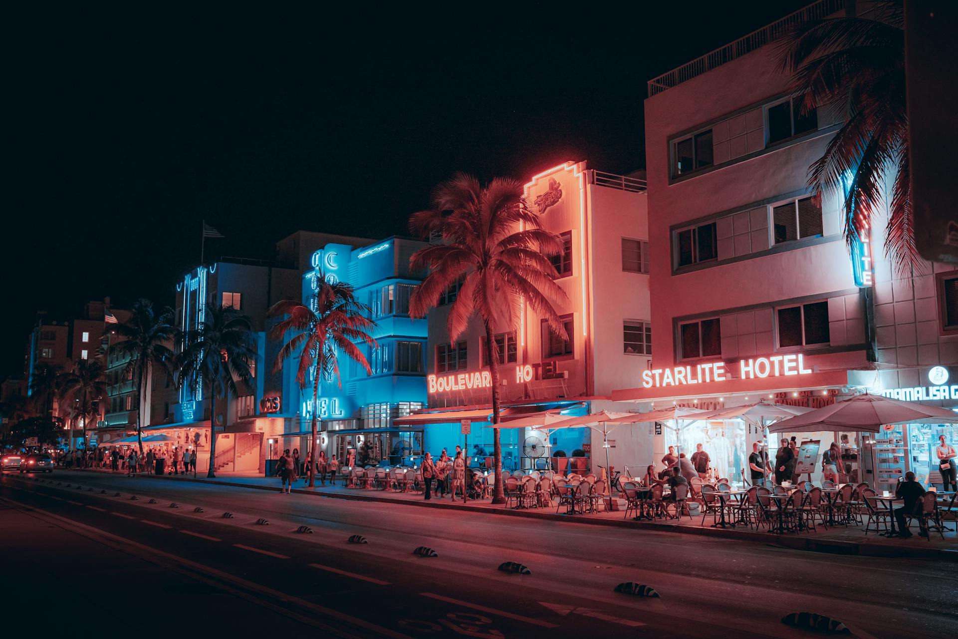 Colorful Art Deco hotels and lively street scene on Ocean Drive at night in Miami Beach.