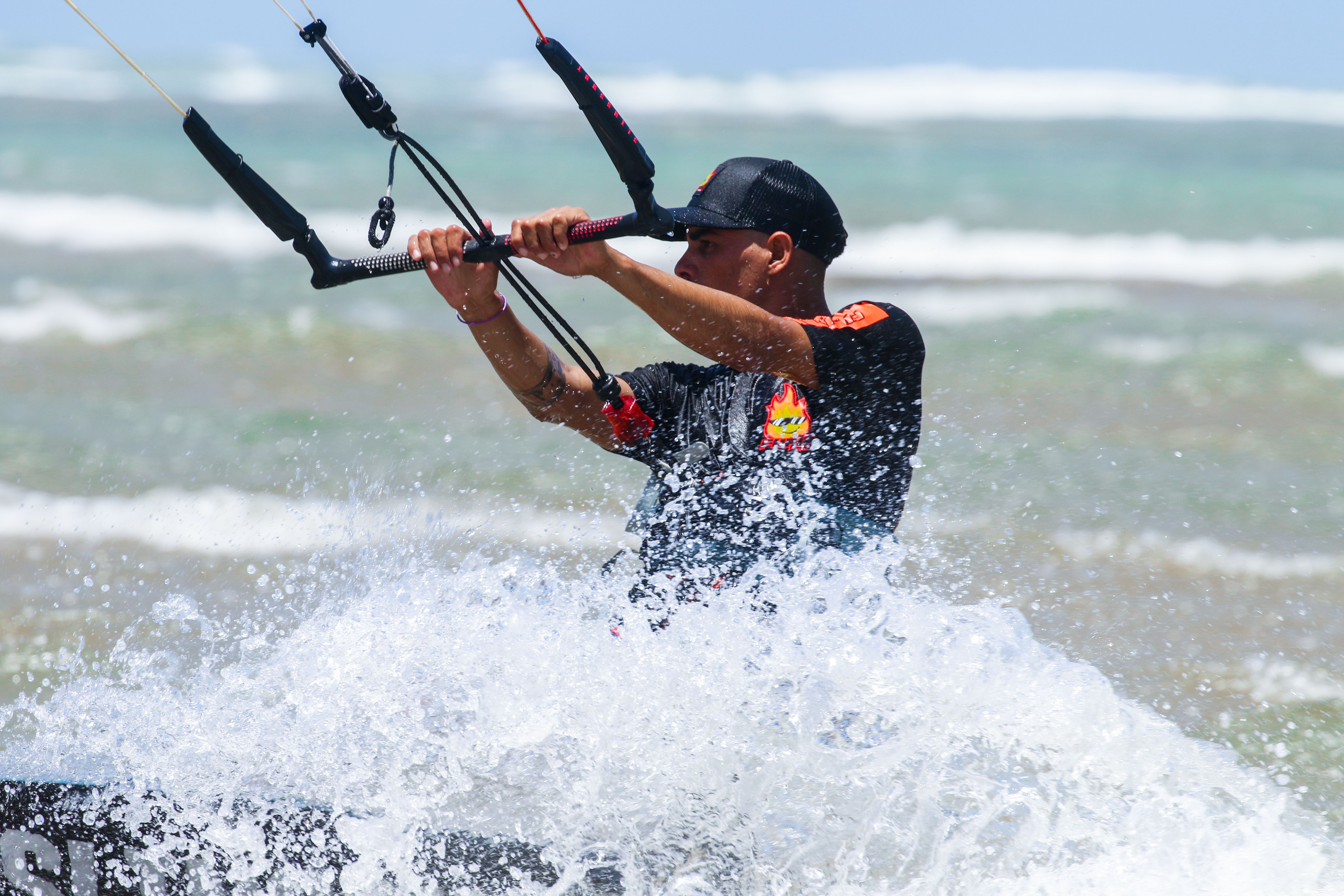 Energetic kitesurfer skillfully navigating ocean waves with splashes, showcasing extreme sports excitement.